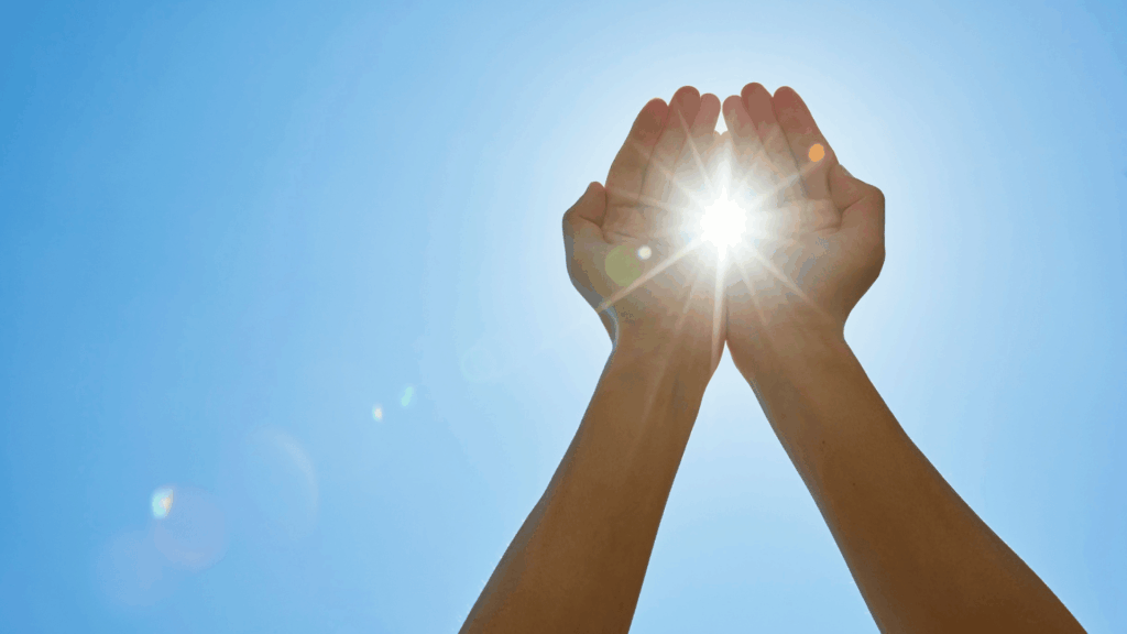 Hands holding the sun against an energy transition landscape