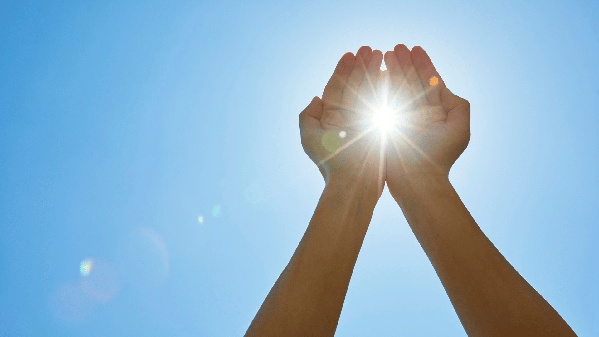 Hands holding the sun against an energy transition landscape